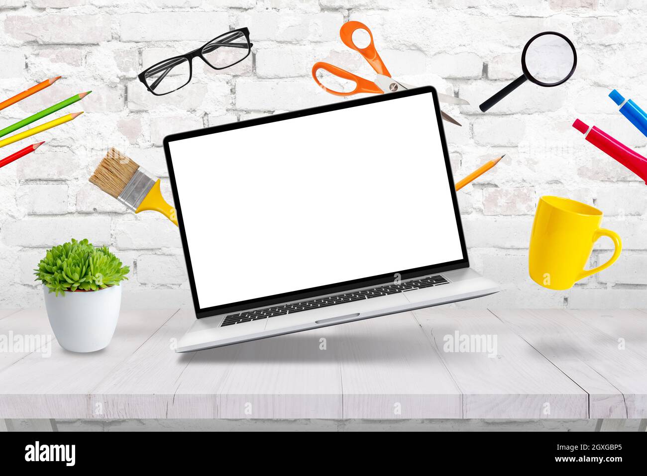 Laptop mockup levitating with creative  office supplies above the desk concept Stock Photo
