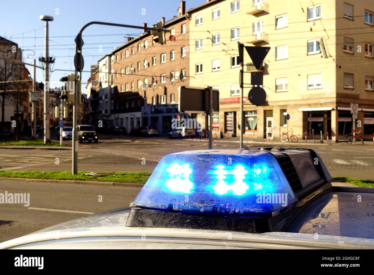 Blue flashing lights on a police car in a town in Germany. Houses, cars