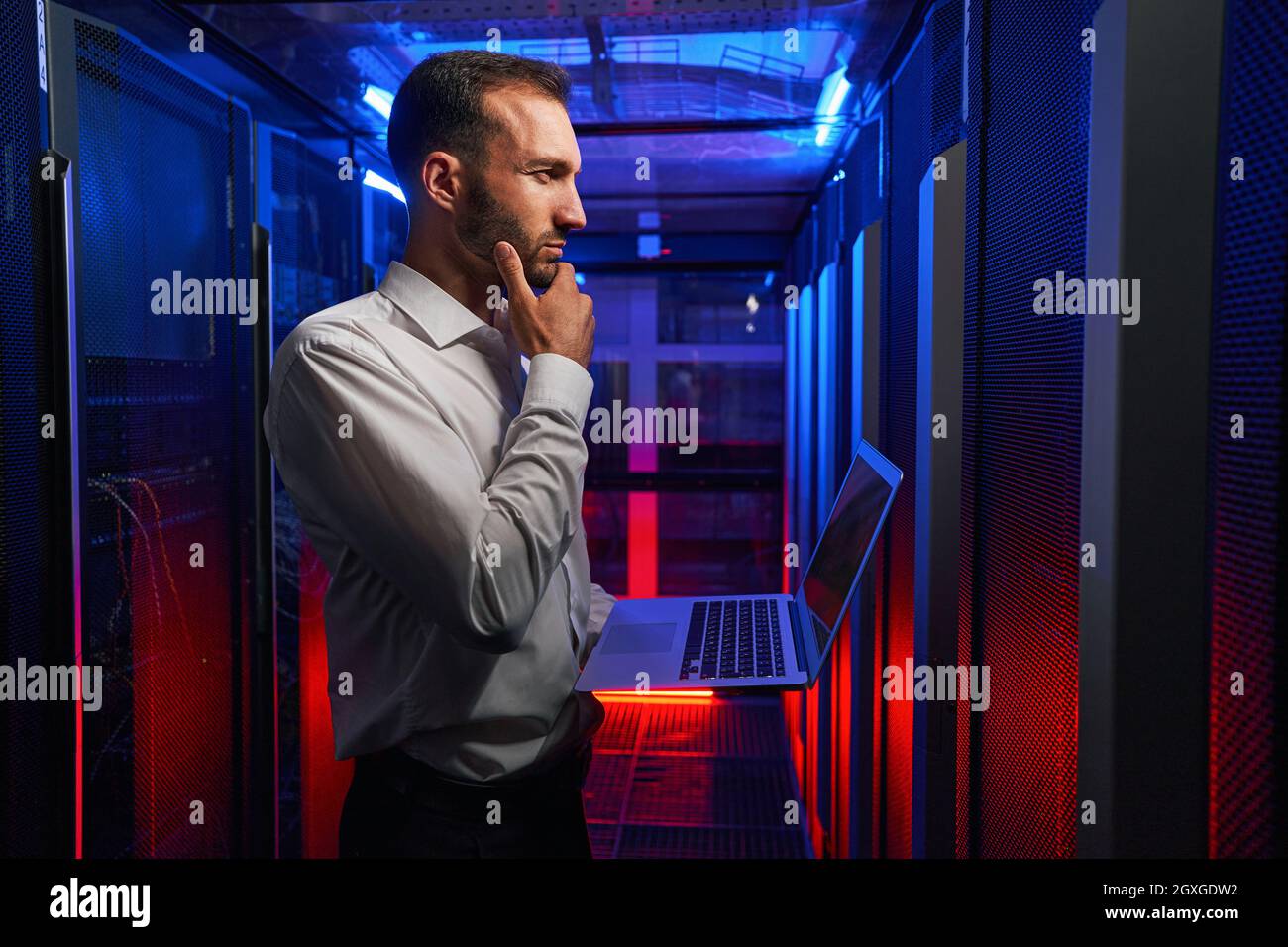 Bearded concentrated network engineer examining work of supercomputer in tech place Stock Photo