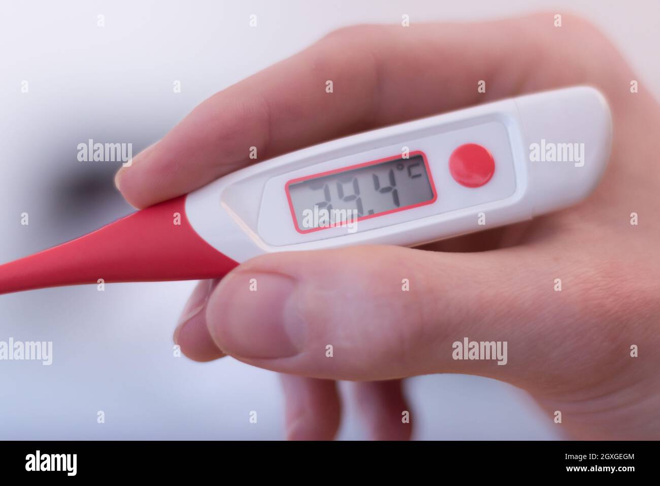 Man holds a red fever thermometer with 39 degrees Celsius in his hand Stock  Photo - Alamy