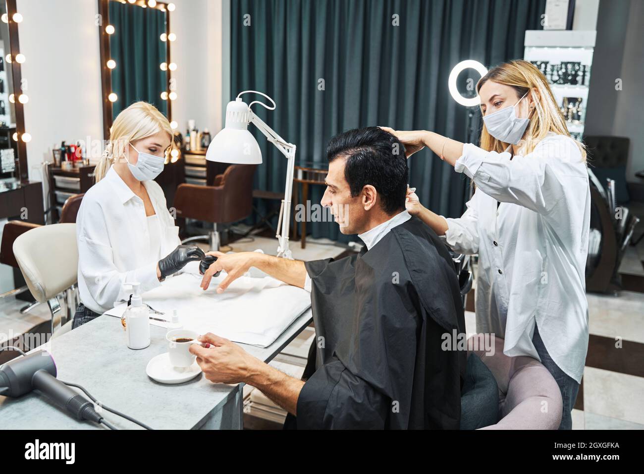 Workers of hair and beauty salon attending to male customer Stock Photo