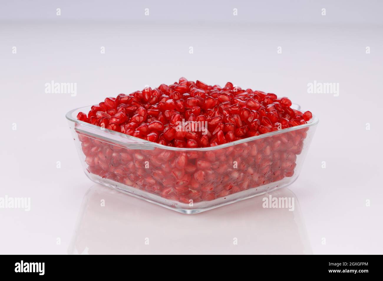 Fresh Pomegranate seed arranged in a square glass container with white background, isolated. Stock Photo