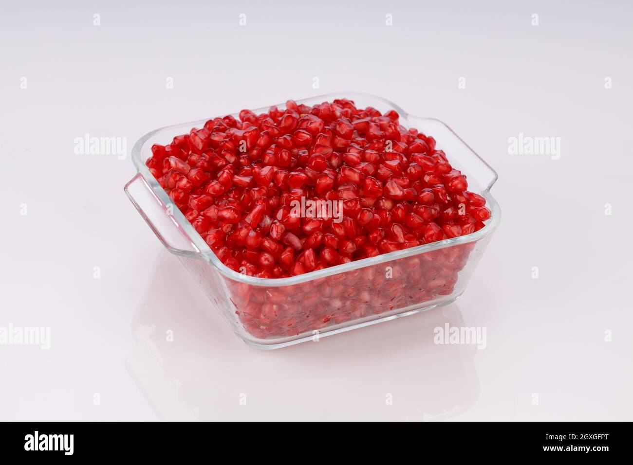 Fresh Pomegranate seed arranged in a square glass container on white background, isolated. Stock Photo