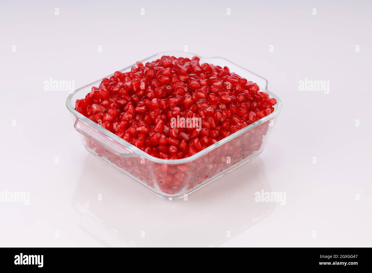 Fresh Pomegranate seed arranged in a square glass container with white background, isolated. Stock Photo