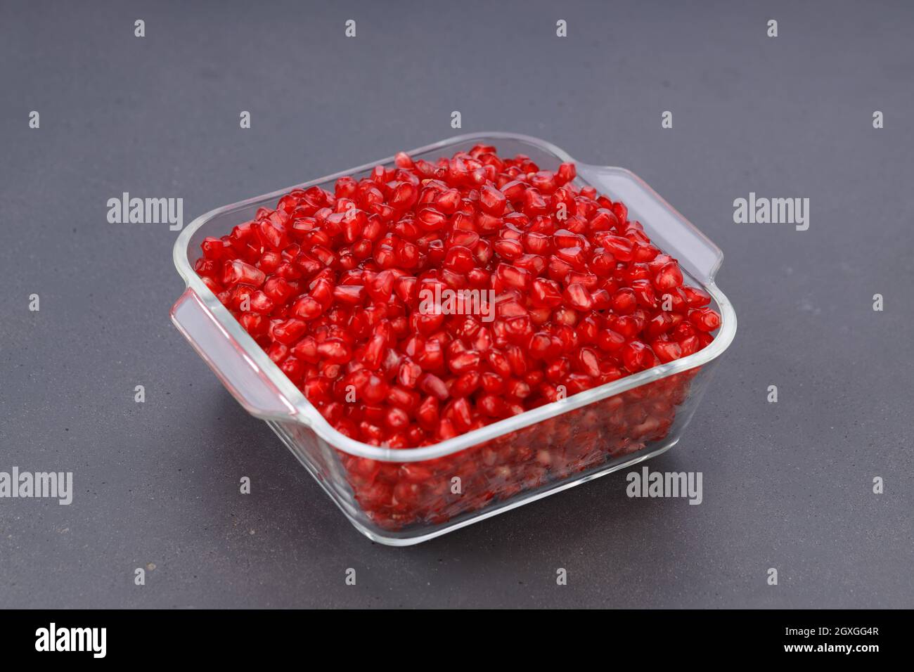 Fresh Pomegranate seed arranged in a square glass container on black background, isolated. Stock Photo