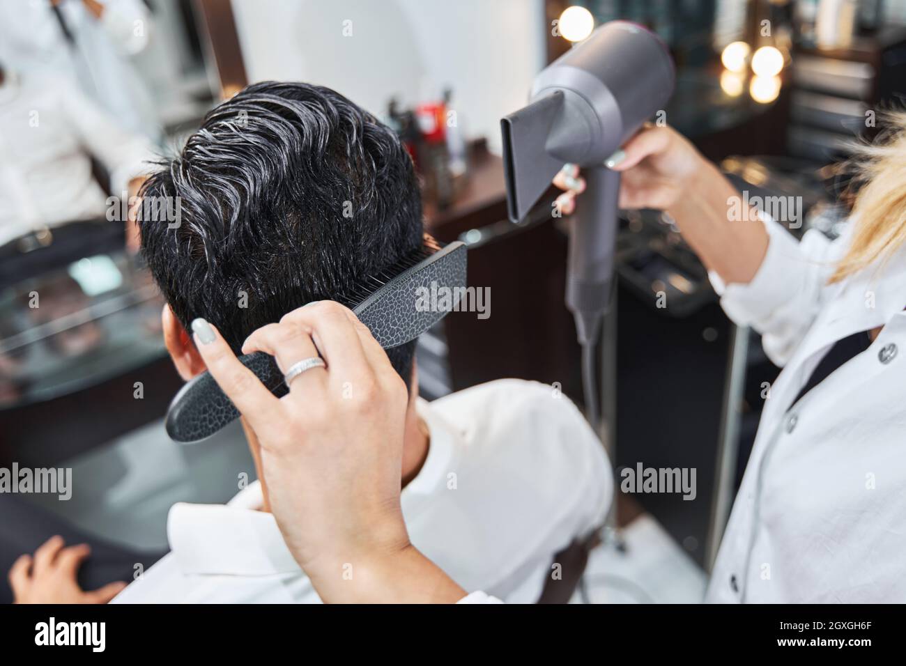 Specialist brushing hair on back of head while using hairdryer Stock