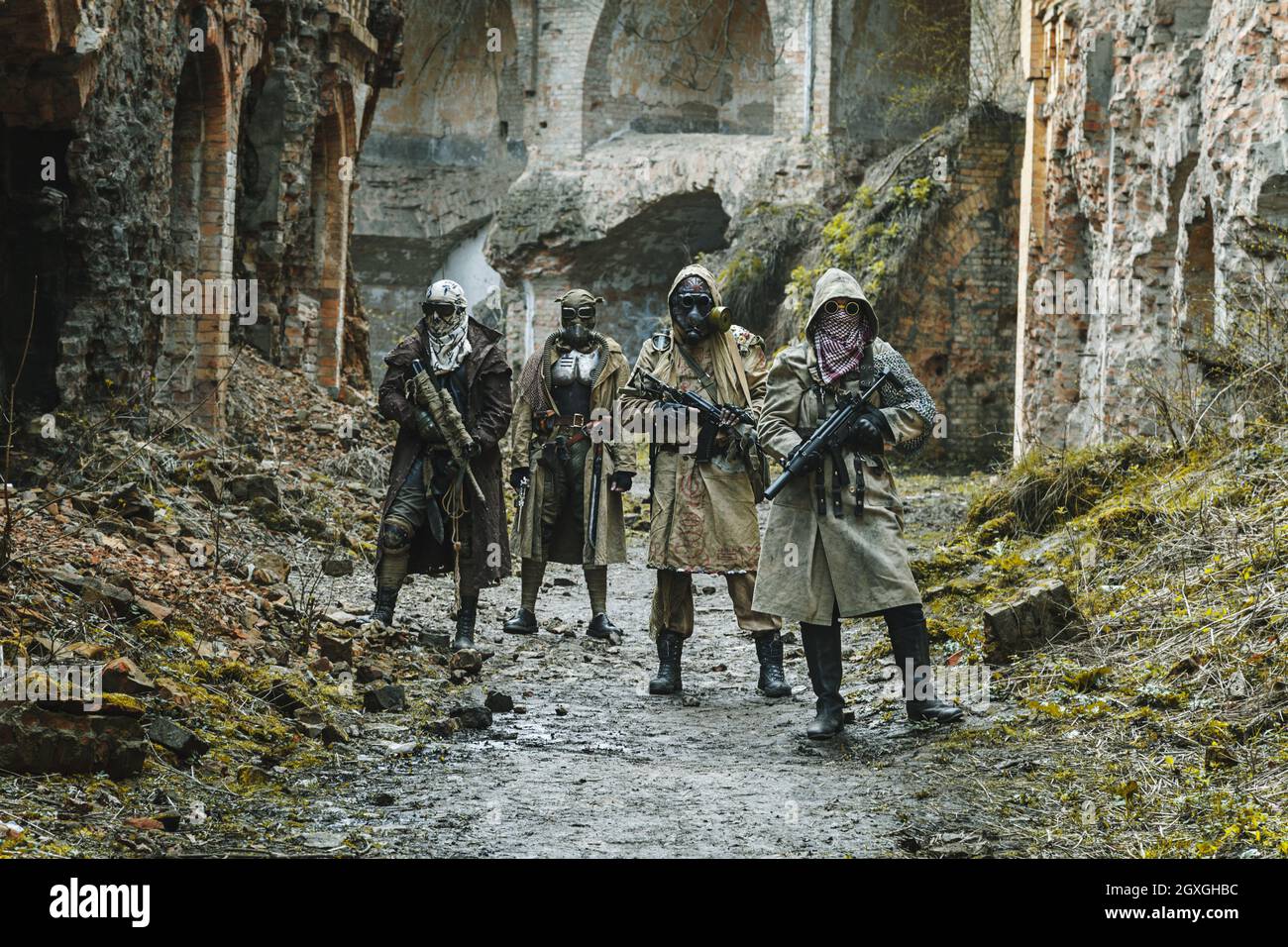 Nuclear post-apocalypse. Survivors in tatters and gas mask on the ruins of the destroyed city Stock Photo