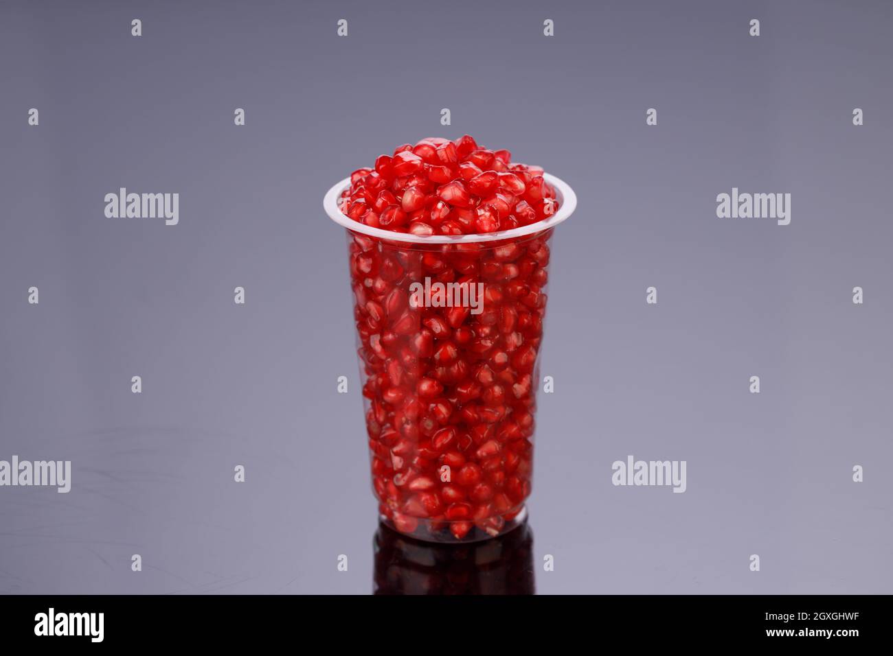 Fresh Pomegranate seed arranged in a  glass container with  black background, isolated. Stock Photo
