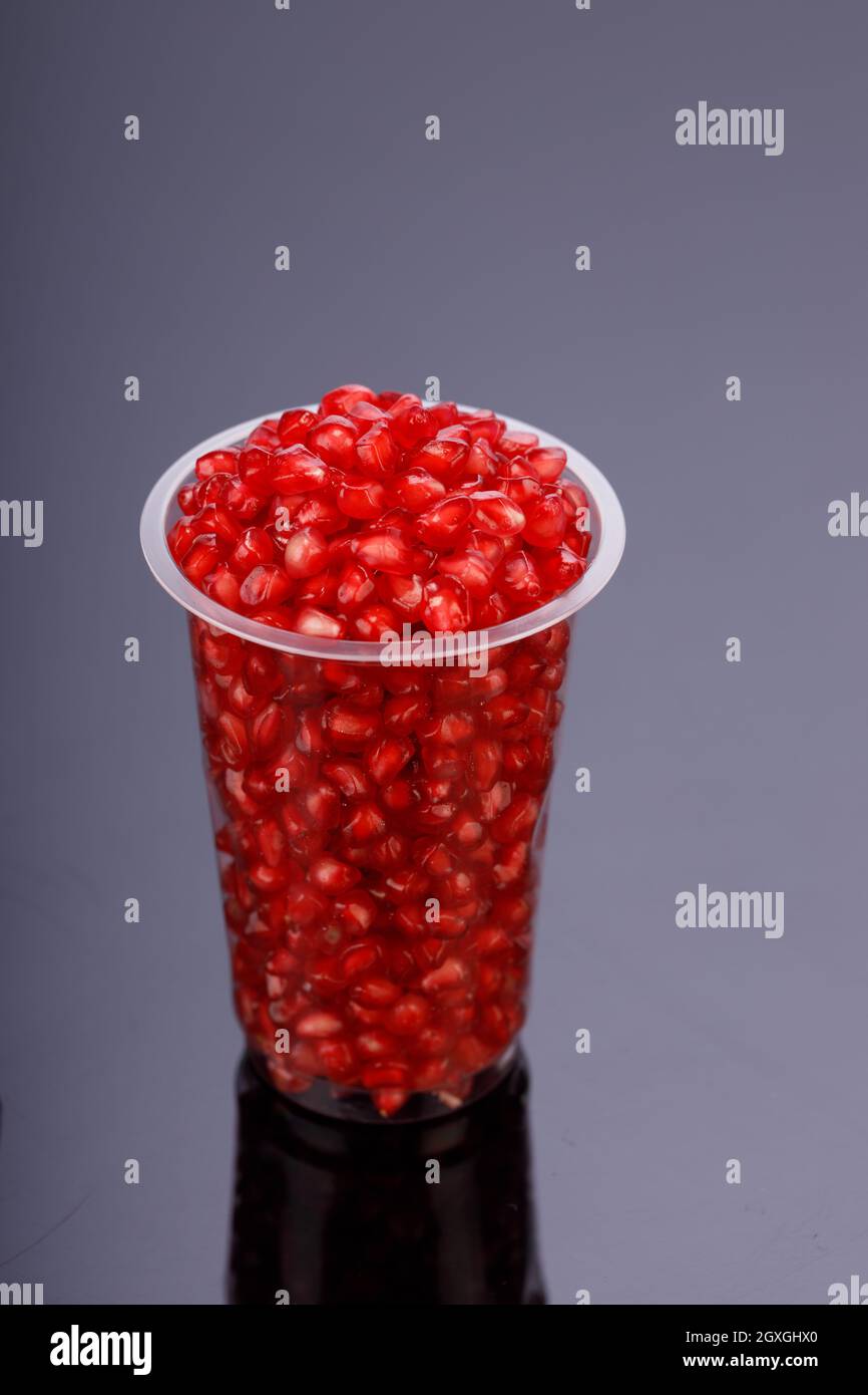 Fresh Pomegranate seed arranged in a  glass container with  black background, isolated. Stock Photo