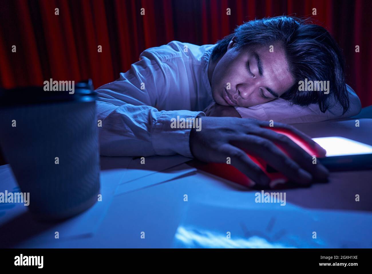 Tired worker sleeping at workplace in evening Stock Photo