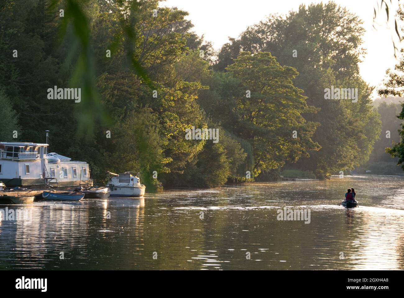 A  Peaceful Evening Scene with two distance Canoes on The Norfolk Broads, Thorpe St Andrew, Norwich, Norfolk, England, UK, Stock Photo