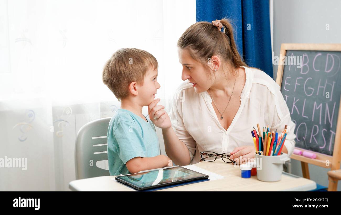 Angry mother looking and talking to her silly little son doing homework ...
