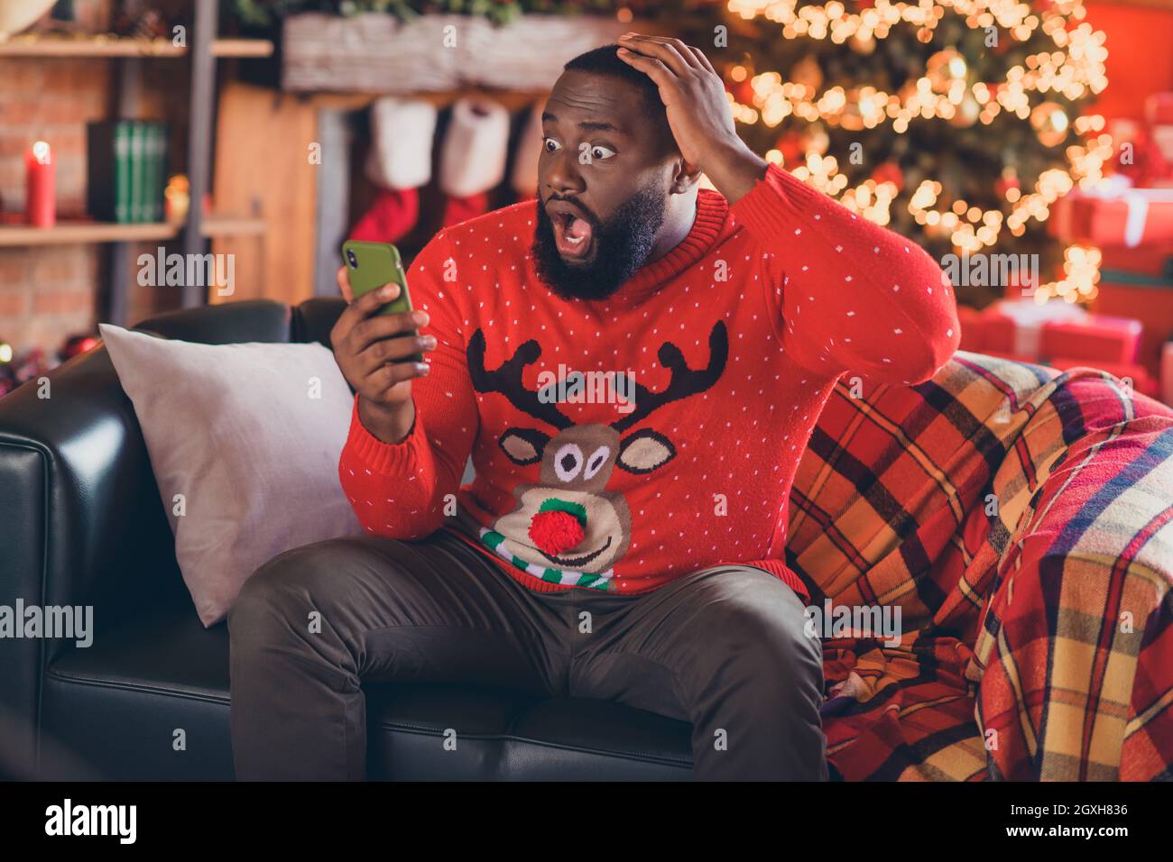 Photo of sad millennial brunet guy look telephone wear red sweater at loft  home new year Stock Photo - Alamy