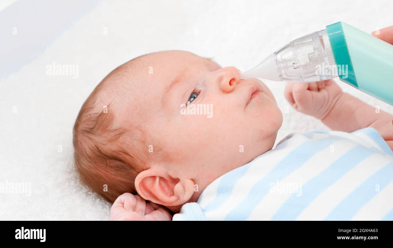 Closeup of mother using electric nasal aspirator to remove mucus from