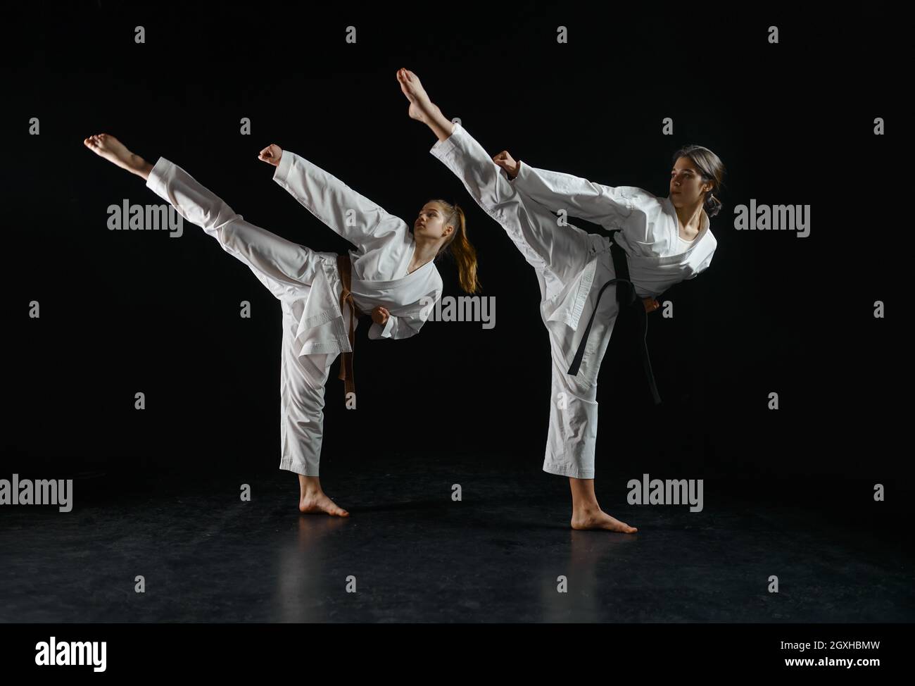 Female karatekas in white kimono, combat stance in action, dark background.  Karate fighters on workout, martial arts, women fighting competition Stock  Photo - Alamy