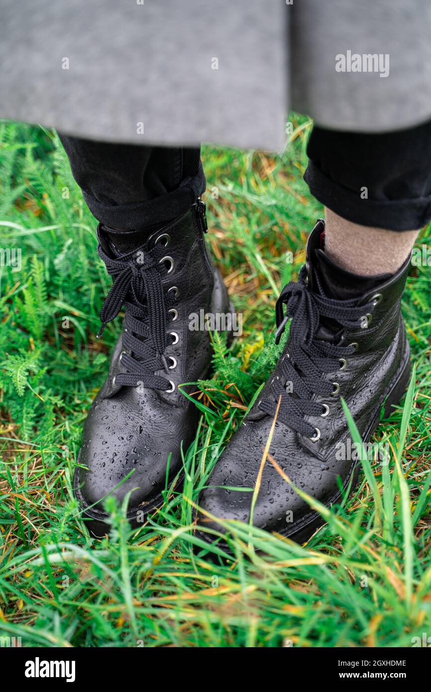 Young woman wearing black leather wet boots in green fresh grass in park  Stock Photo - Alamy