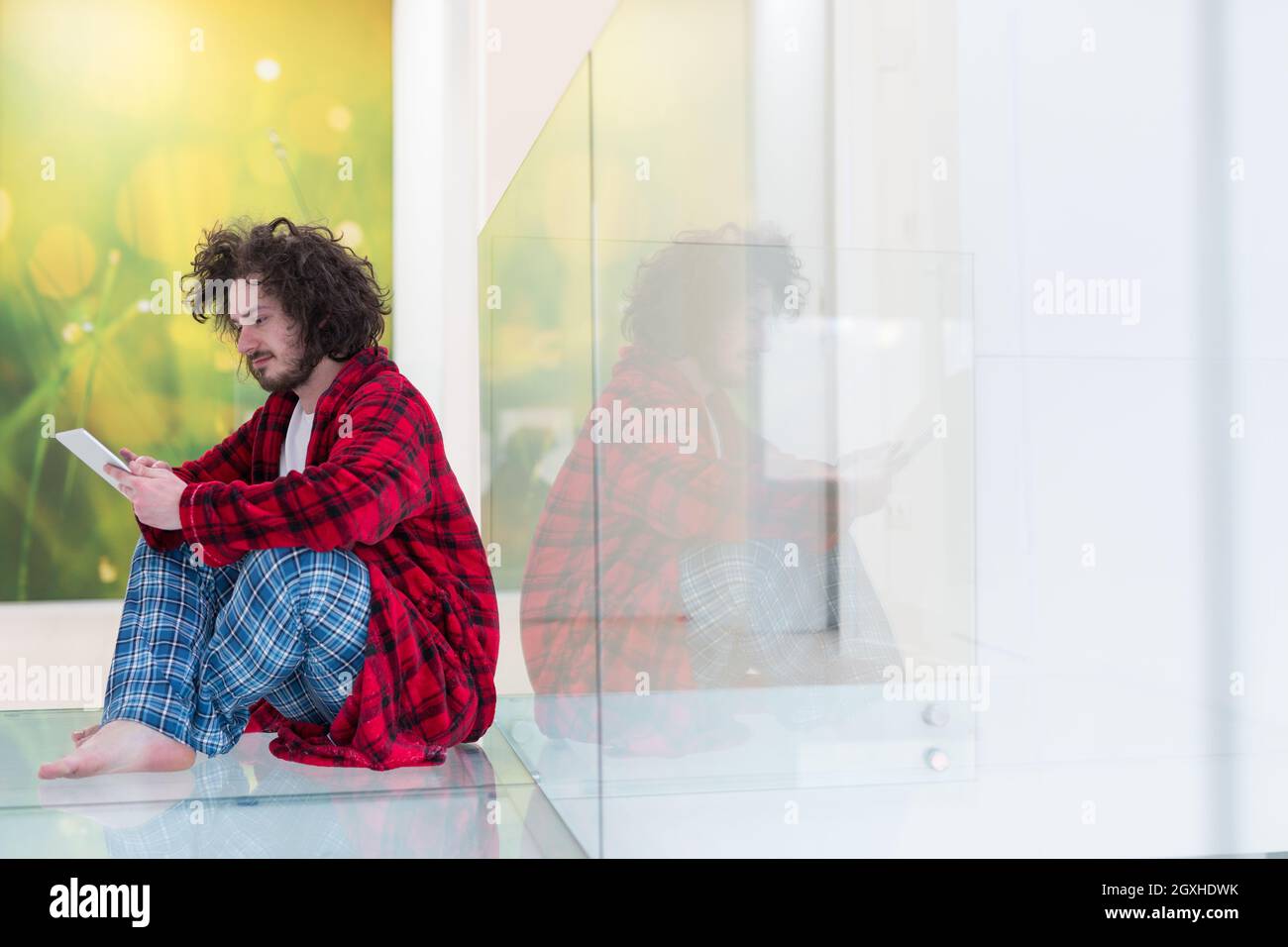 young freelancer in bathrobe working from home using tablet computer Stock Photo