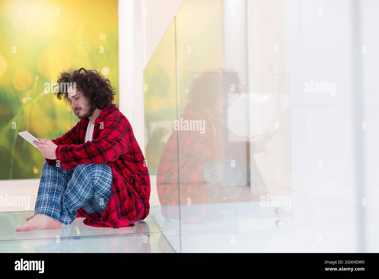 young freelancer in bathrobe working from home using tablet computer Stock Photo