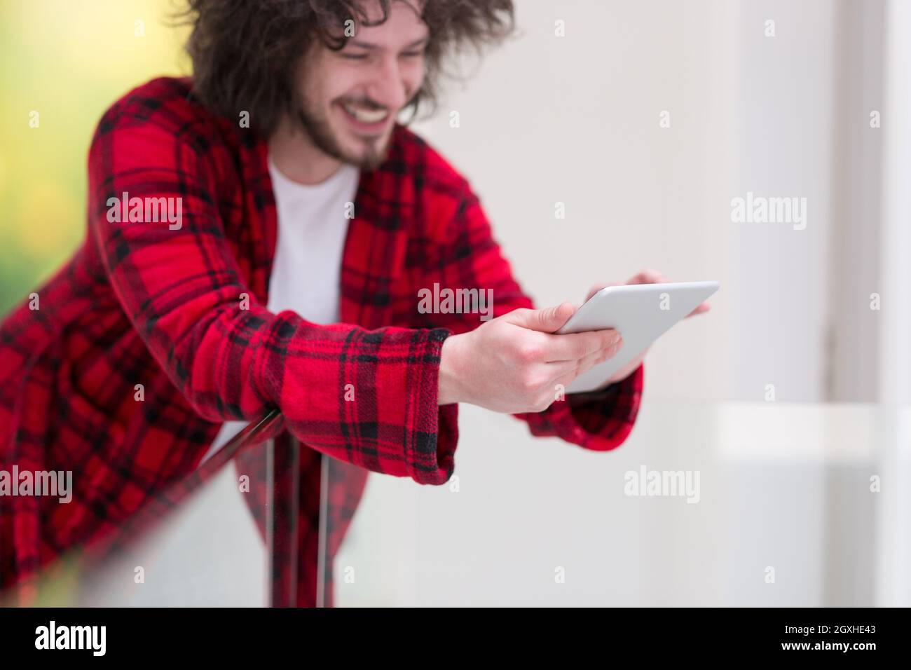 young freelancer in bathrobe working from home using tablet computer Stock Photo