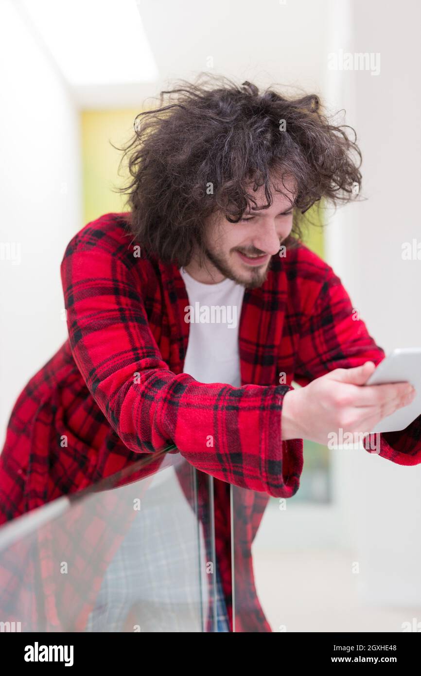 young freelancer in bathrobe working from home using tablet computer Stock Photo
