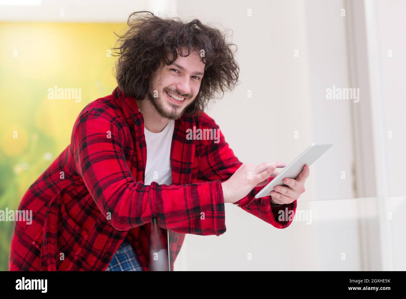 young freelancer in bathrobe working from home using tablet computer Stock Photo