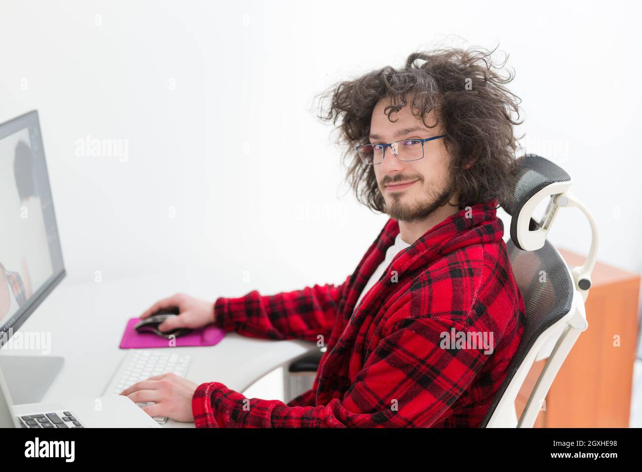 young graphic designer in bathrobe working at home office using computer Stock Photo