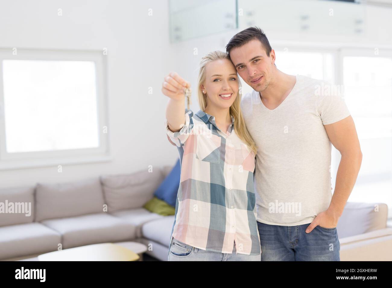 Happy smiling young couple hugging while showing a keys of their new ...