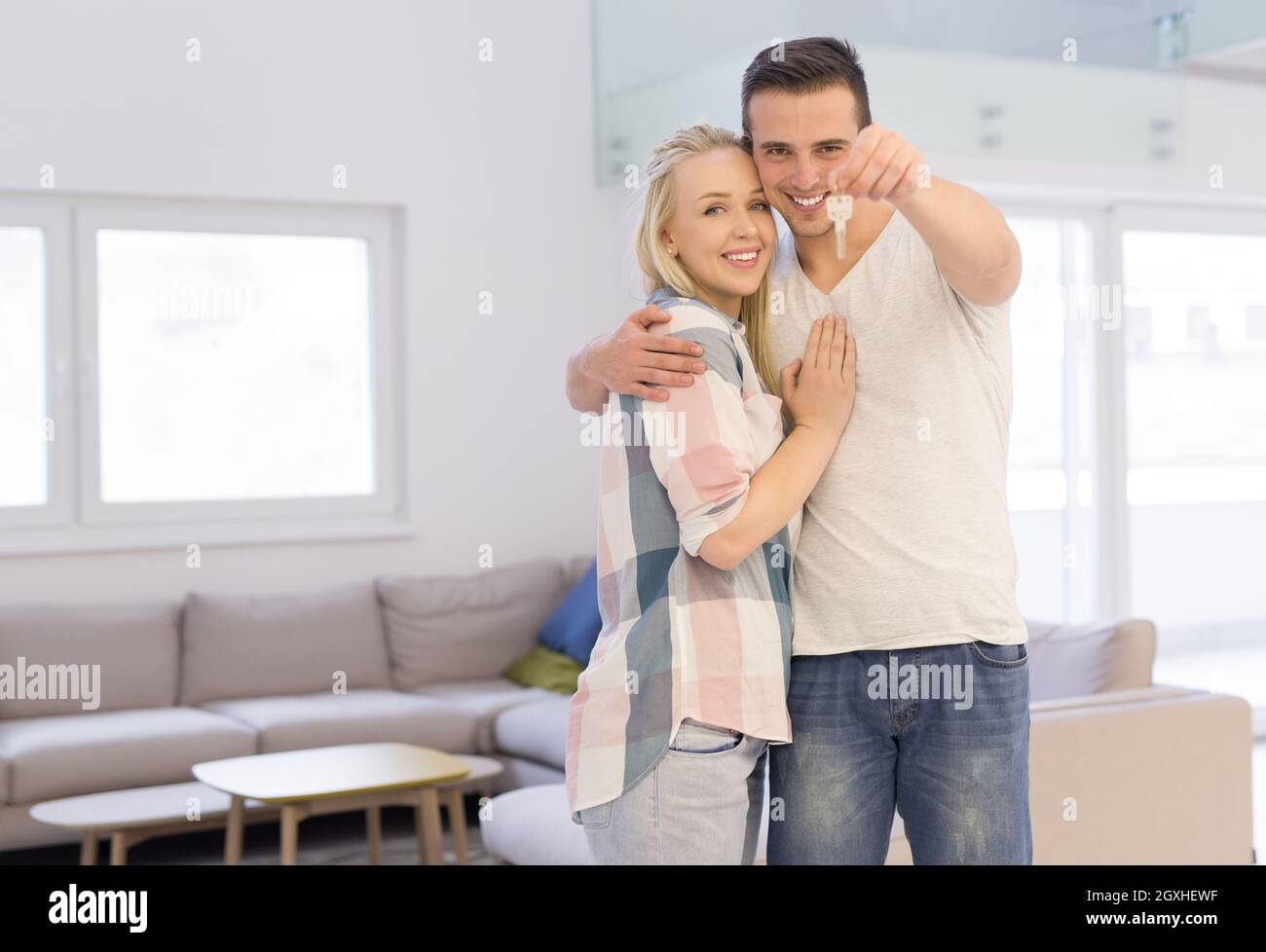 Happy smiling young couple hugging while showing a keys of their new ...