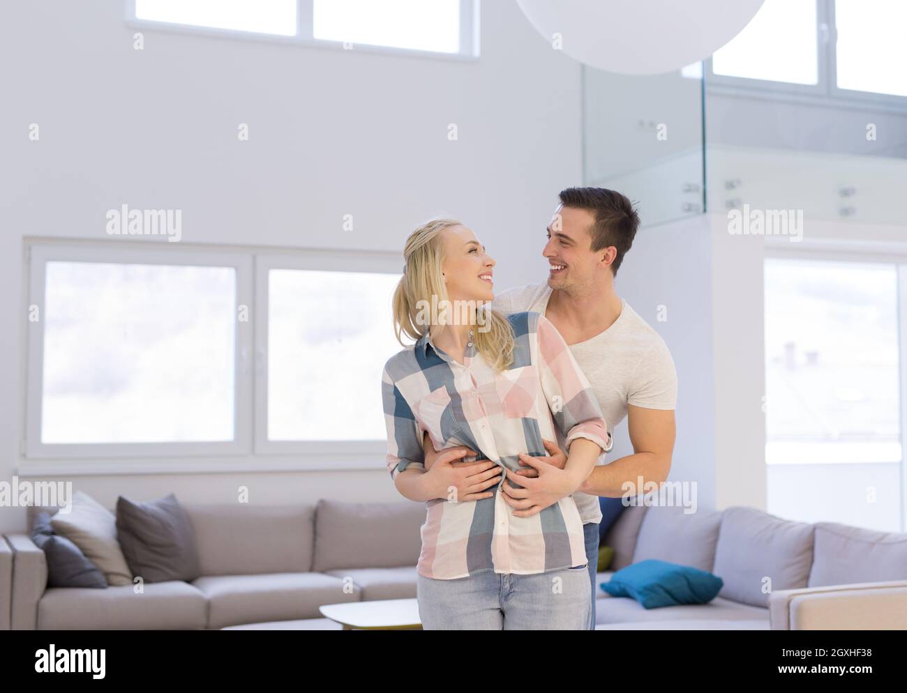 Portrait of a happy young beautiful couple hugging in their new home ...
