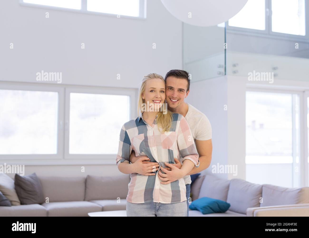Portrait of a happy young beautiful couple hugging in their new home ...