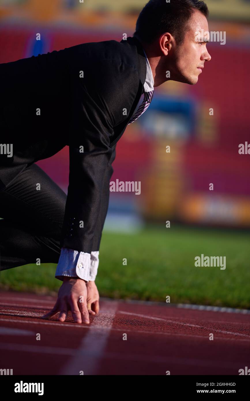 business man in start position ready to run and sprint on athletics racing track Stock Photo