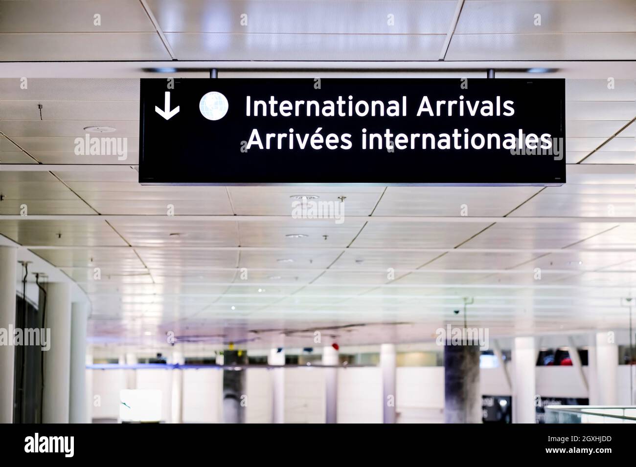 International arrivals sign board in english and french at airport terminal hall. Government open border for international travellers visitors. Stock Photo