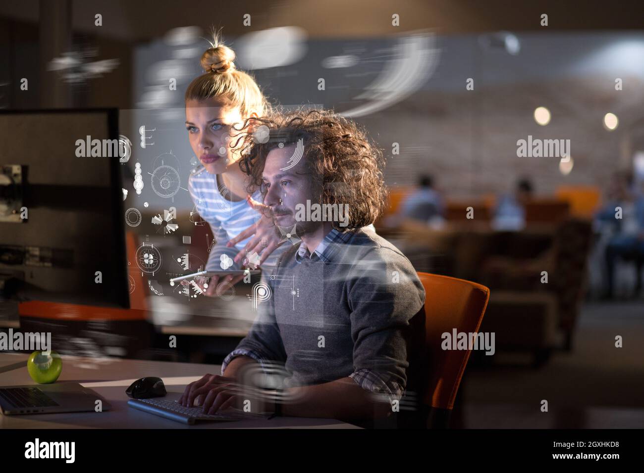 Two young designers are working on a new project in the night office using modern technology Stock Photo