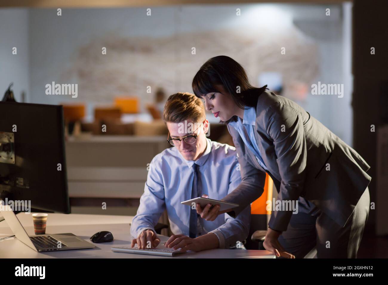 Two young designers are working on a new project in the night office using modern technology Stock Photo