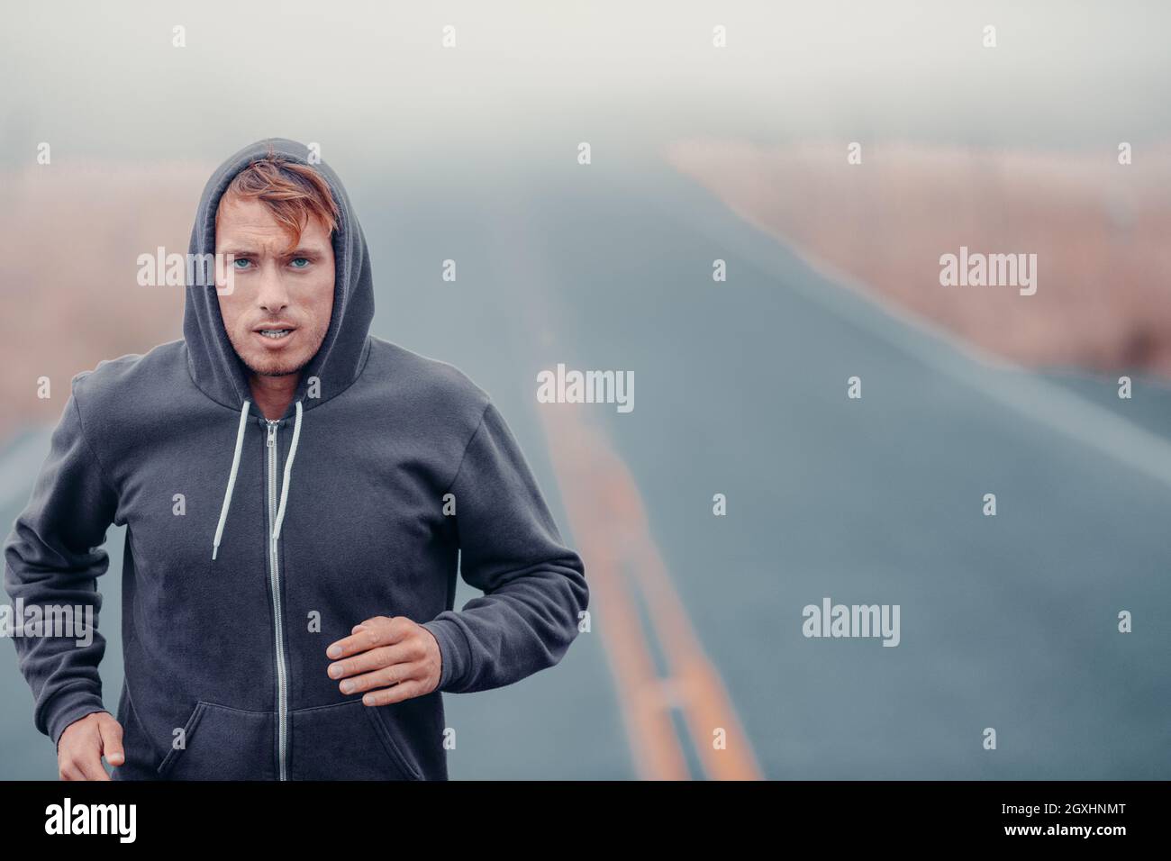 Morning run endurance runner athlete running outside in cold winter training cardio. Man breathing while jogging outdoors in hoody Stock Photo