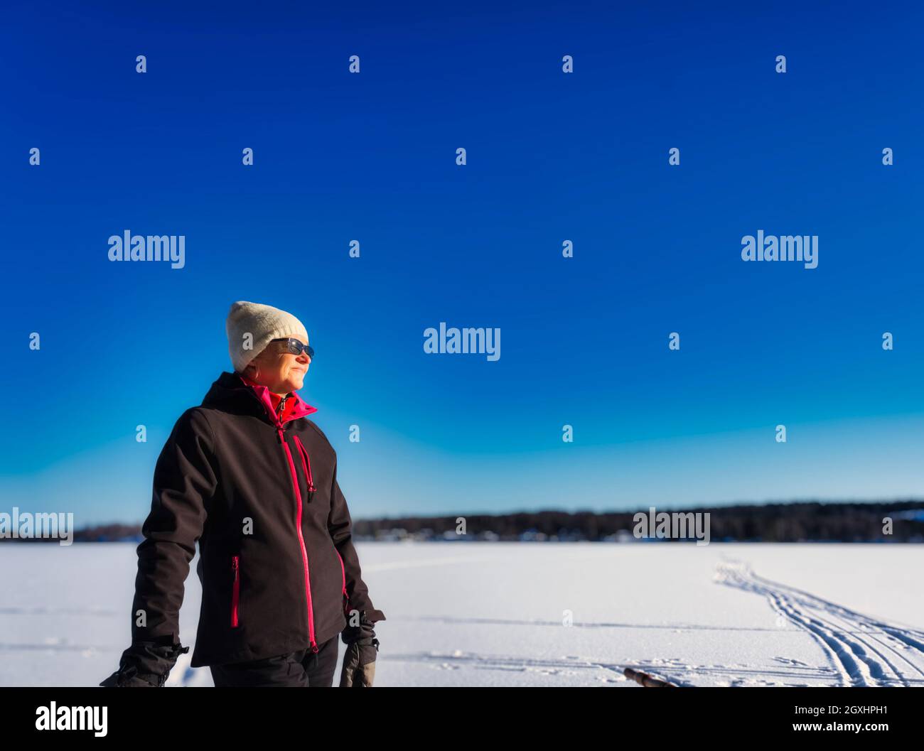 Winter dressed woman standing on a frozen lake with clear blue sky Stock Photo