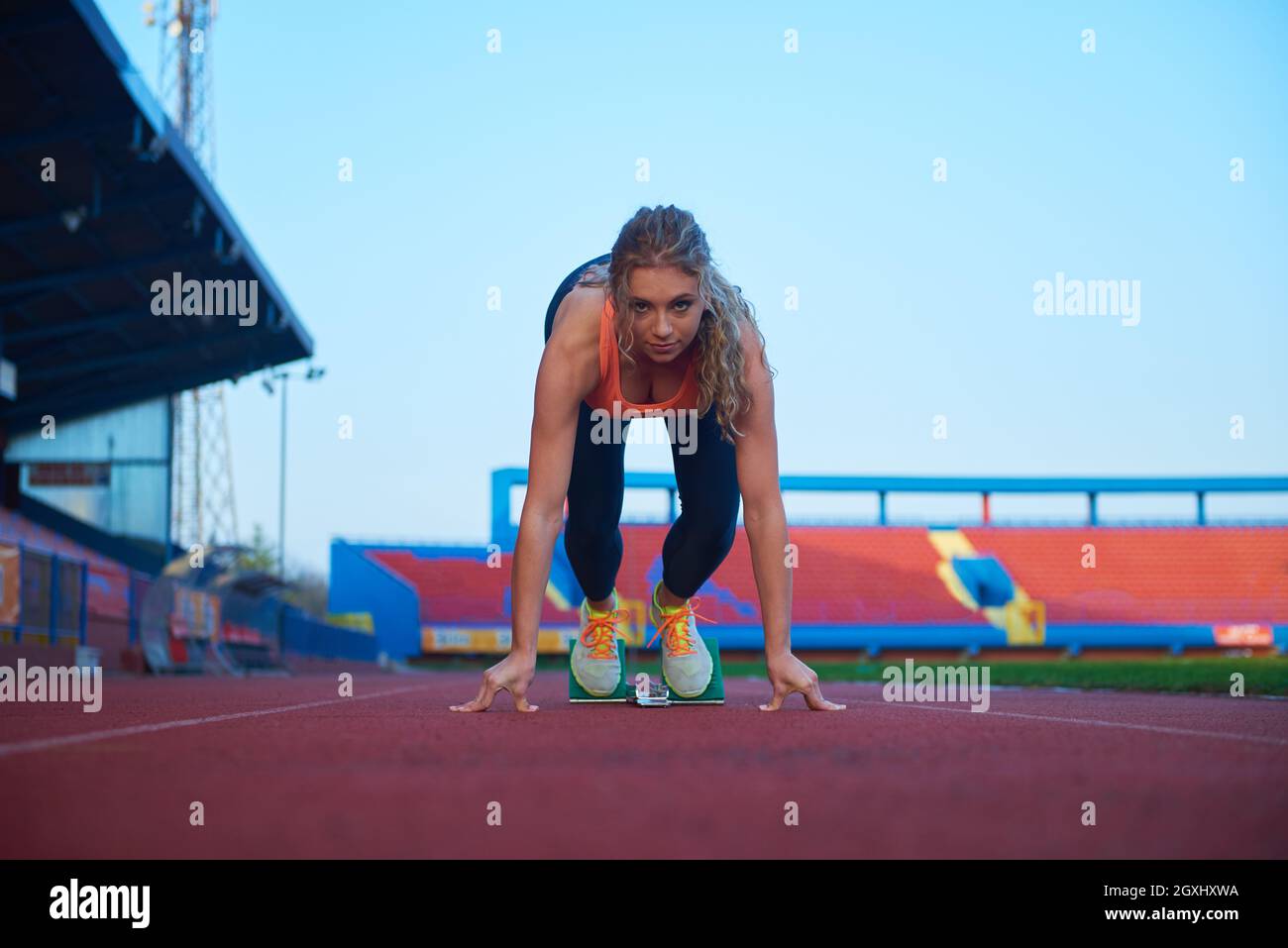 woman  sprinter leaving starting blocks on the athletic  track. Side view. exploding start Stock Photo