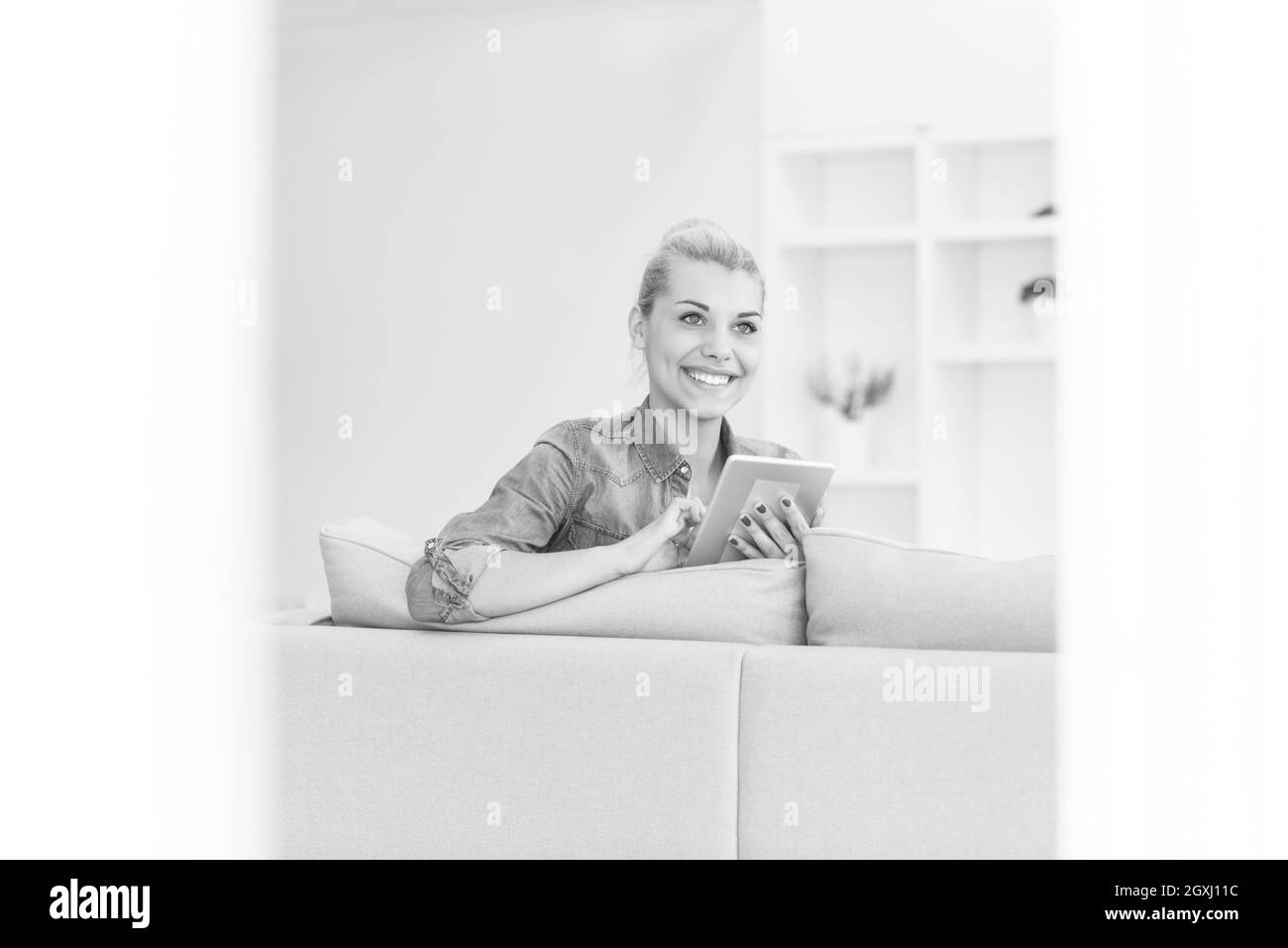 young happy woman on sofa using tablet computer at luxury home Stock Photo