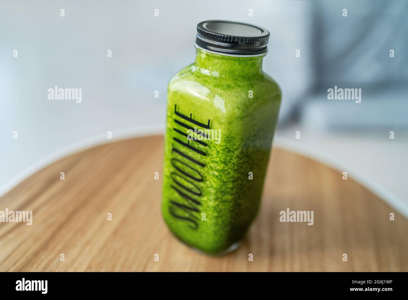 Green smoothie detox healthy breakfast to go drink celery juice diet bottle with text title SMOOTHIE on cafe table or home kitchen Stock Photo