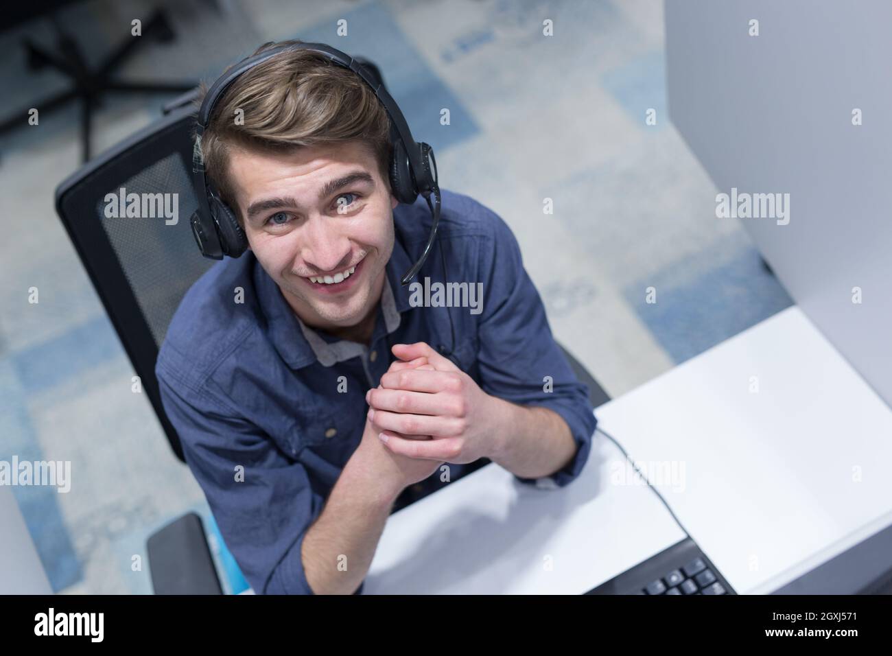 top view of a young smiling male call centre operator doing his job ...