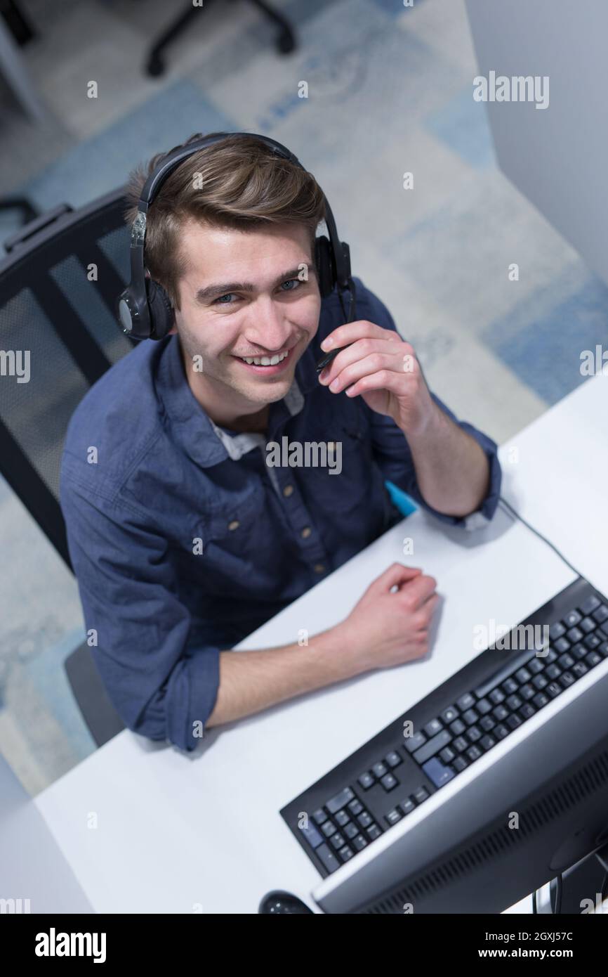 top view of a young smiling male call centre operator doing his job with a headset Stock Photo