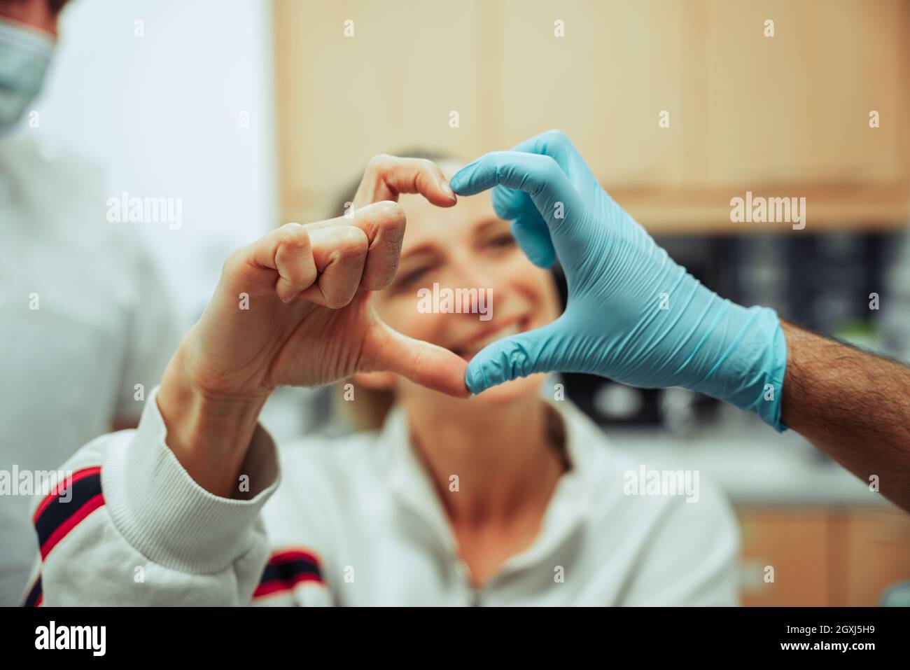 Caucasian female teen enjoying monthly check up at the dentist forming heart shape with hands