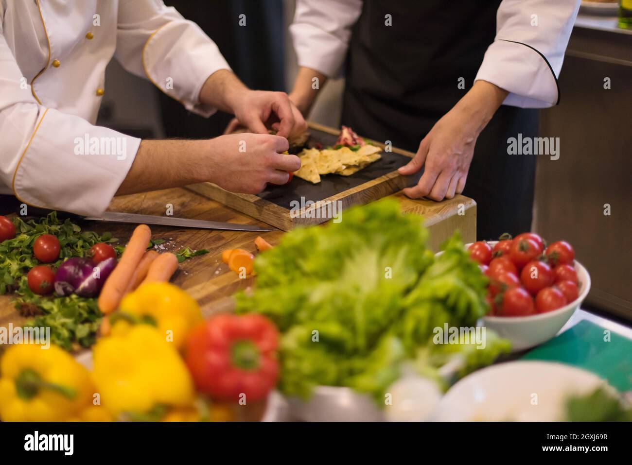 Professional team cooks and chefs preparing meal at busy hotel or ...