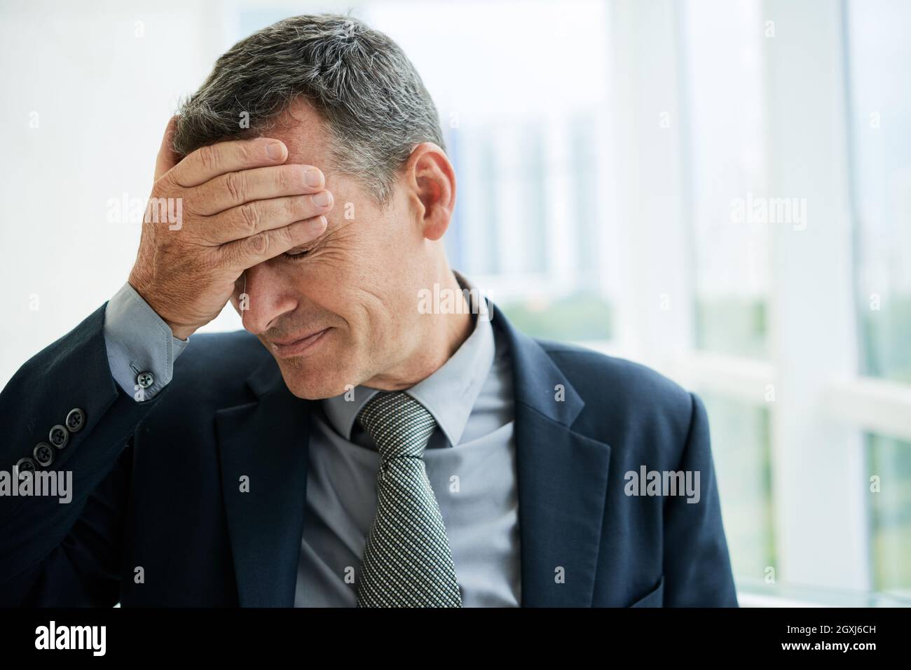 Tired or dissappointed mature male executive in necktie touching