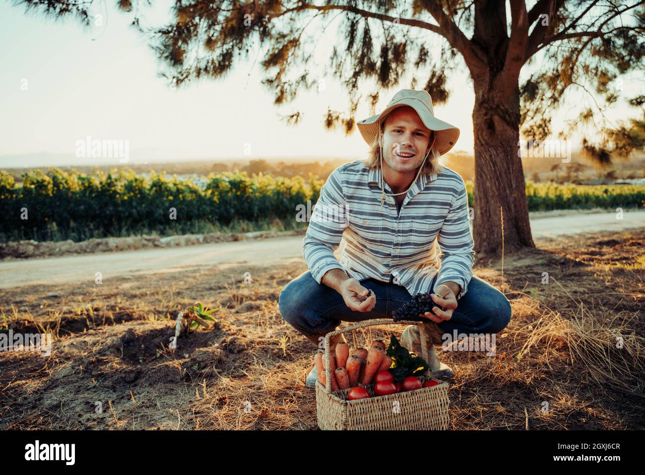 Caucasian blonde male farmer examining freshly picked vegetables in garden Stock Photo