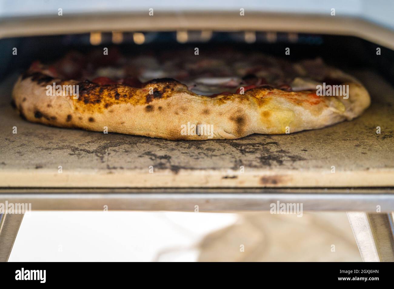Making homemade pizza in portable high temperature gas pizza oven. Delicious pizza is baking in gas oven furnace for home made Neapolitan pizza. Speci Stock Photo