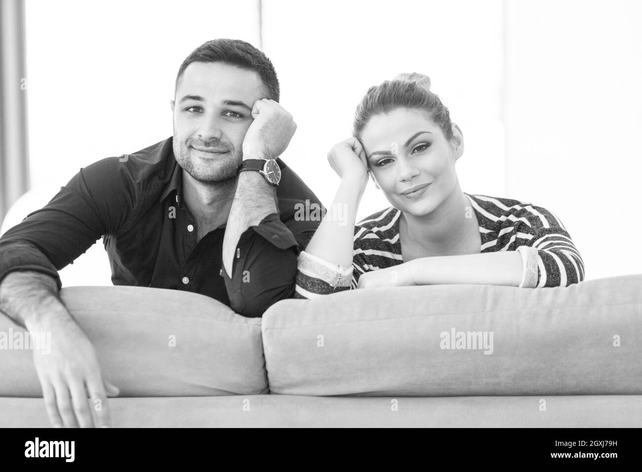 Portrait of young couple sitting on sofa in modern white apartment Stock Photo