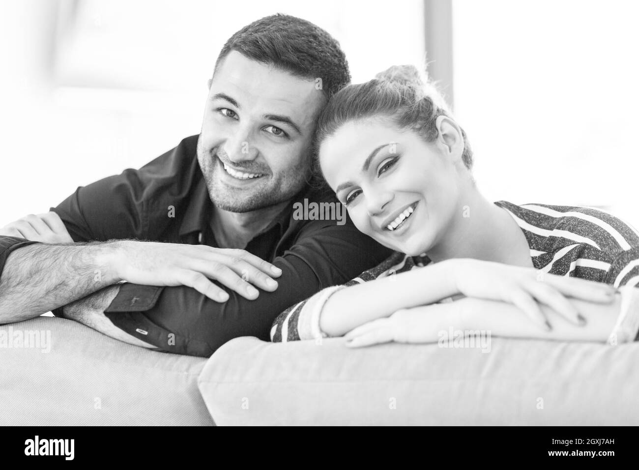 Portrait of young couple sitting on sofa in modern white apartment Stock Photo