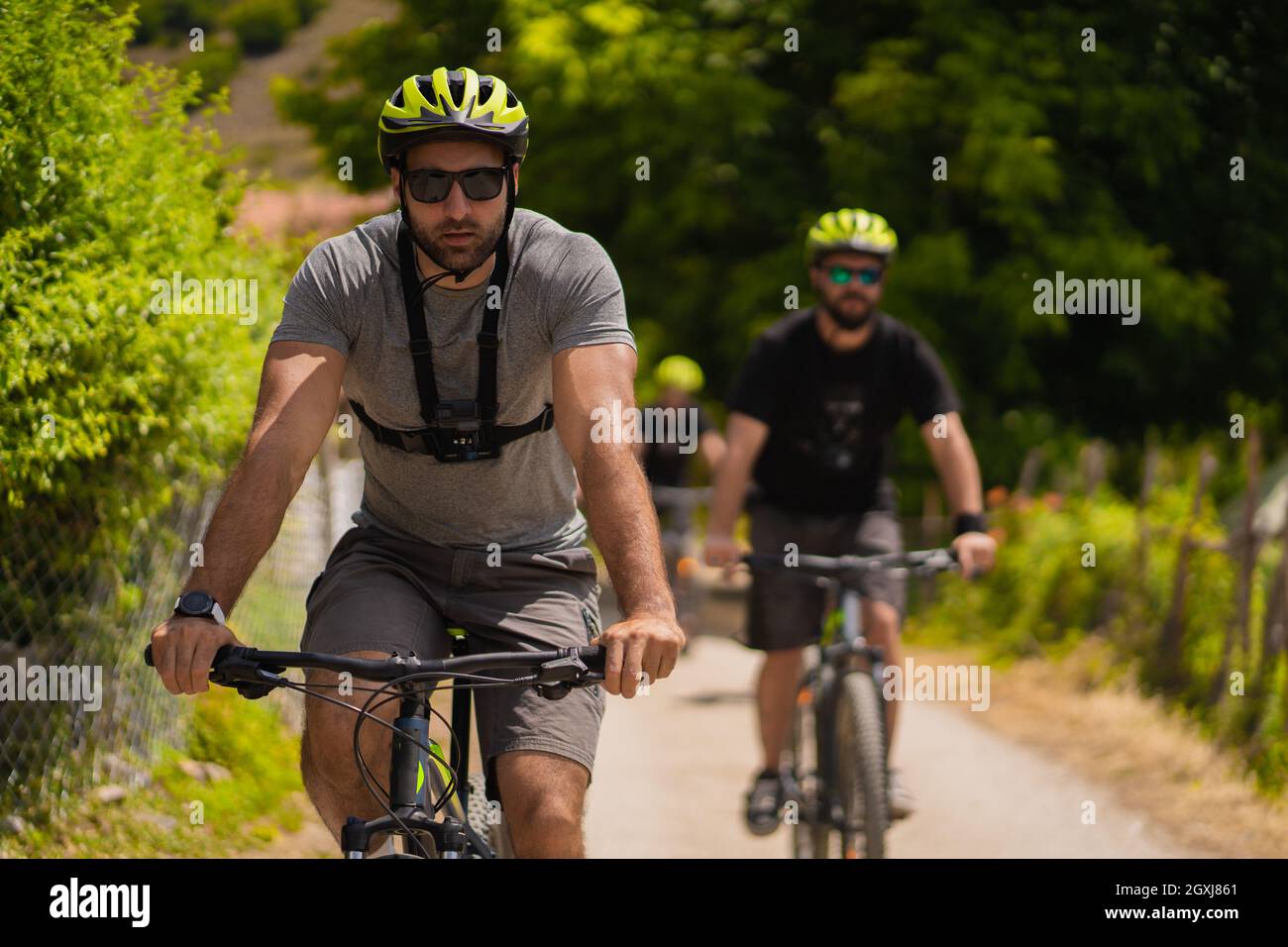 Portrait of handsome and fit guy riding a bike while being followed fom the group Stock Photo