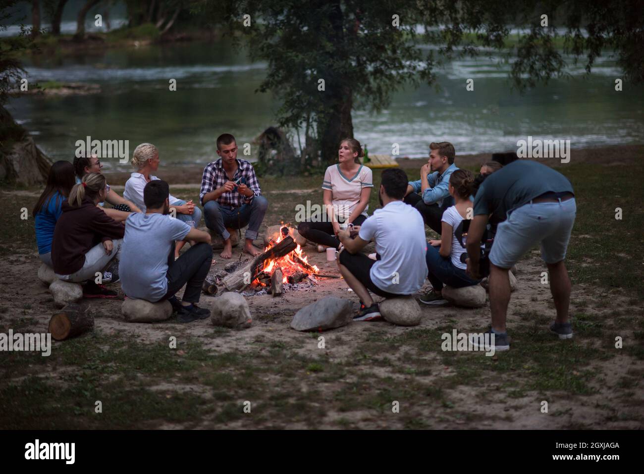 a group of happy young friends relaxing and enjoying summer evening ...